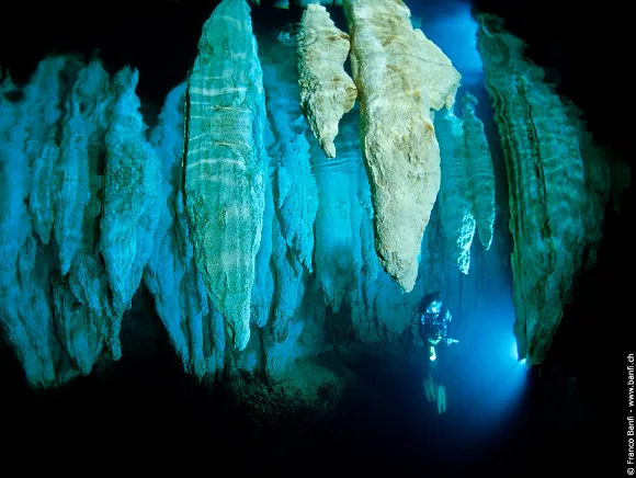 underwater photo of a diver inside Chandelier cave with its stalactites in Palau by Franco Banfi
