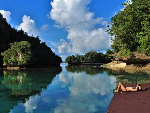 Photo of a girl sun bathing on a dock in the famous Rock Islands of Palau