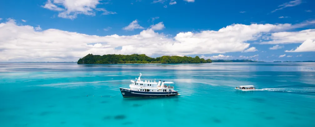Ocean Hunter Liveaboard Palau in blue water in front of an island in Palau