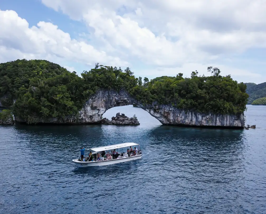The Arch, a natural arch in the rock islands in Palau with a Fish 'n Fins Boat in the foreground