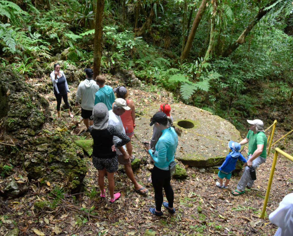 Group of people standing around a stone money in Palau