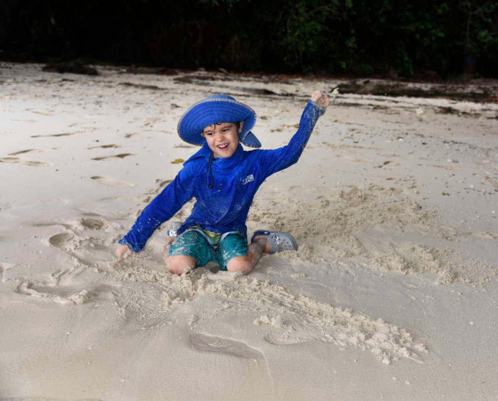 Little boy playing in the sand at Lee Marvin Beach in Palau during an Indiana Jones Tour with Fish 'n Fins