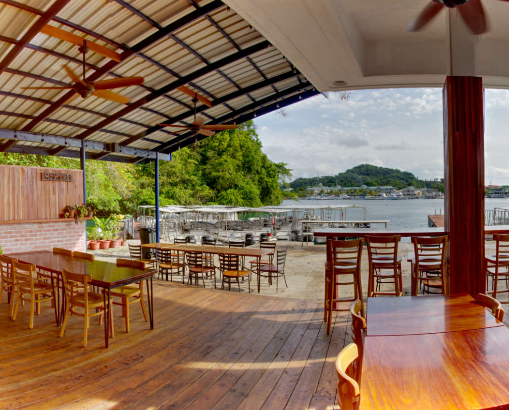 Inside Barracuda Restaurant, showing tables and chairs, looking towards the Fish 'n Fins docks and the sea