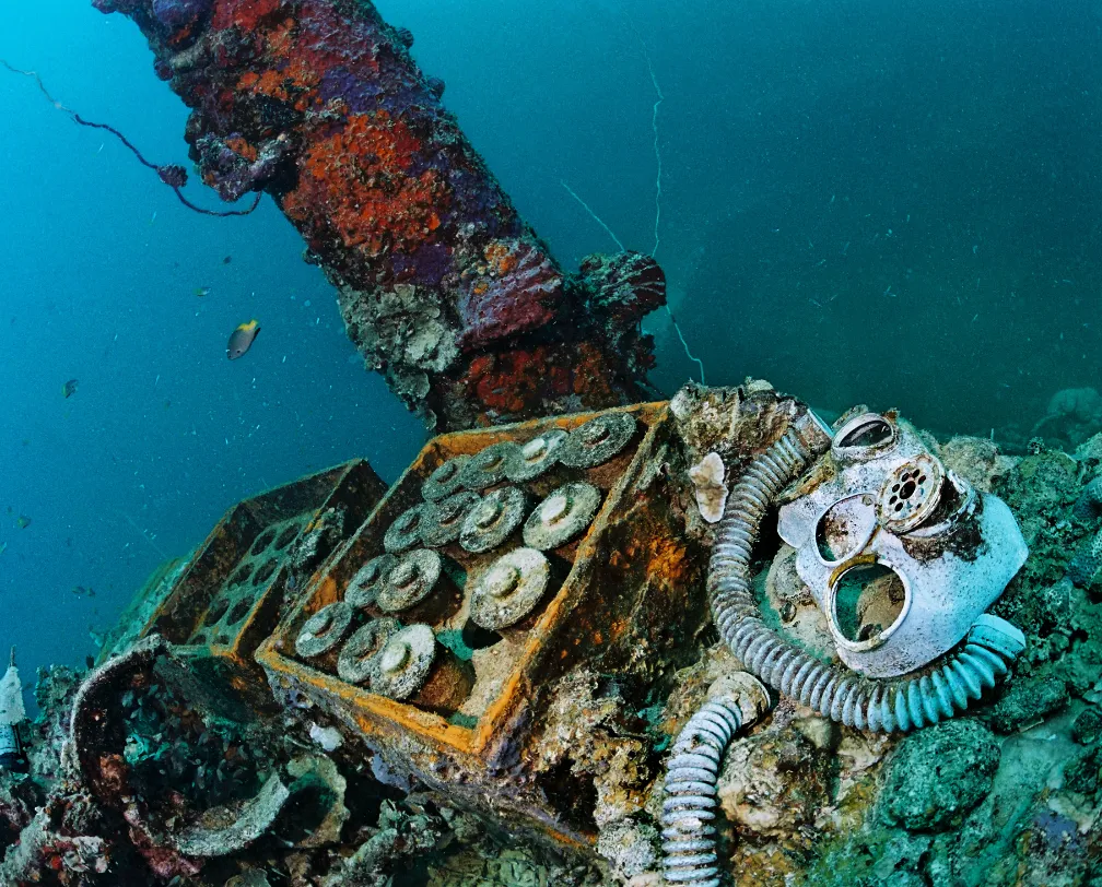 underwater photo of wreck parts like shells and gas masks in a wreck in Palau