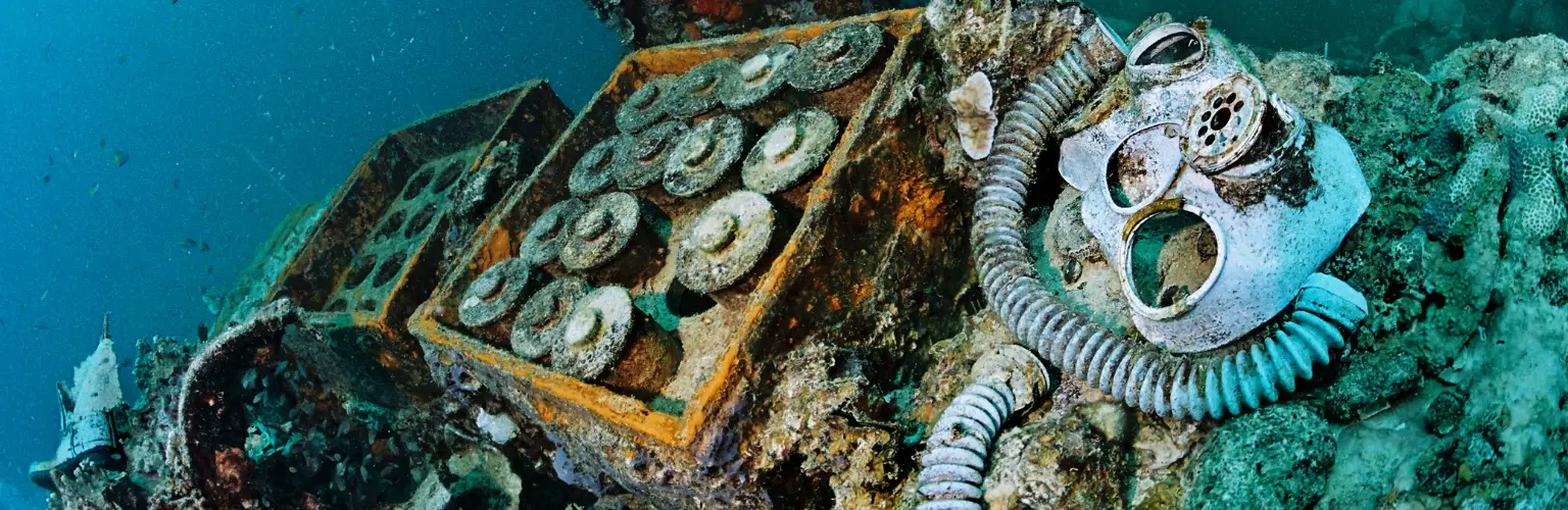 underwater photo of shells, boxes and gas masks of a wreck in Palau